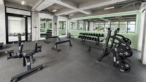 Une salle de sport équipée de matériel de musculation, de bancs et d’haltères.