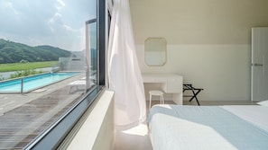 Un dormitorio con vista a una piscina, una cama, un escritorio y una silla.