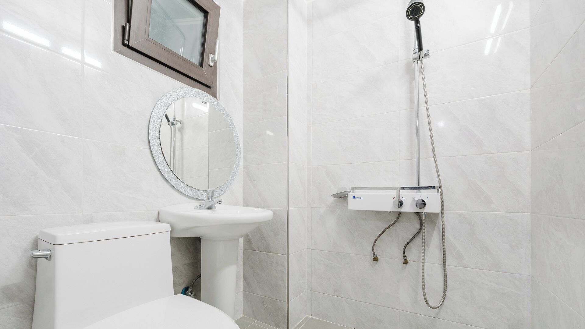Une salle de bain comprenant des toilettes, un lavabo, un miroir et une douche.