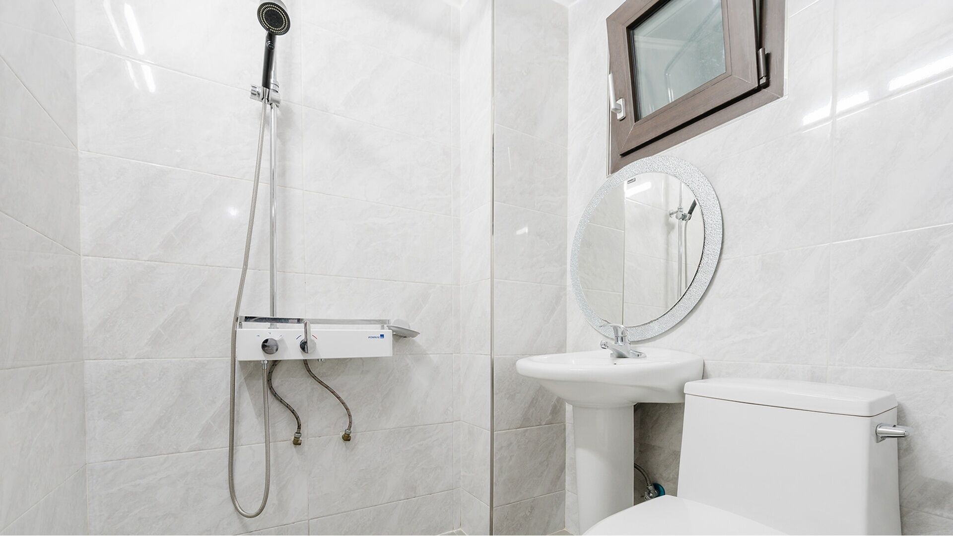 Een badkamer met douche, toilet, wastafel en spiegel.