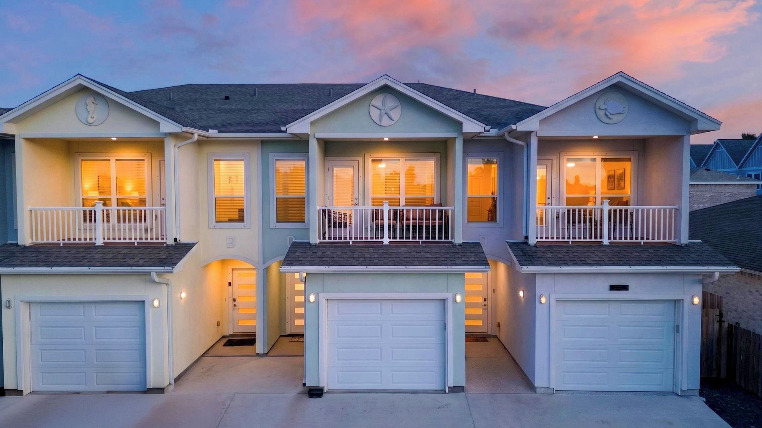 A row of three two-story houses with attached garages, featuring balconies and a uniform architectural style.