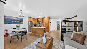 A modern kitchen with wooden cabinets, a central island, and a dining area with a table and chairs.