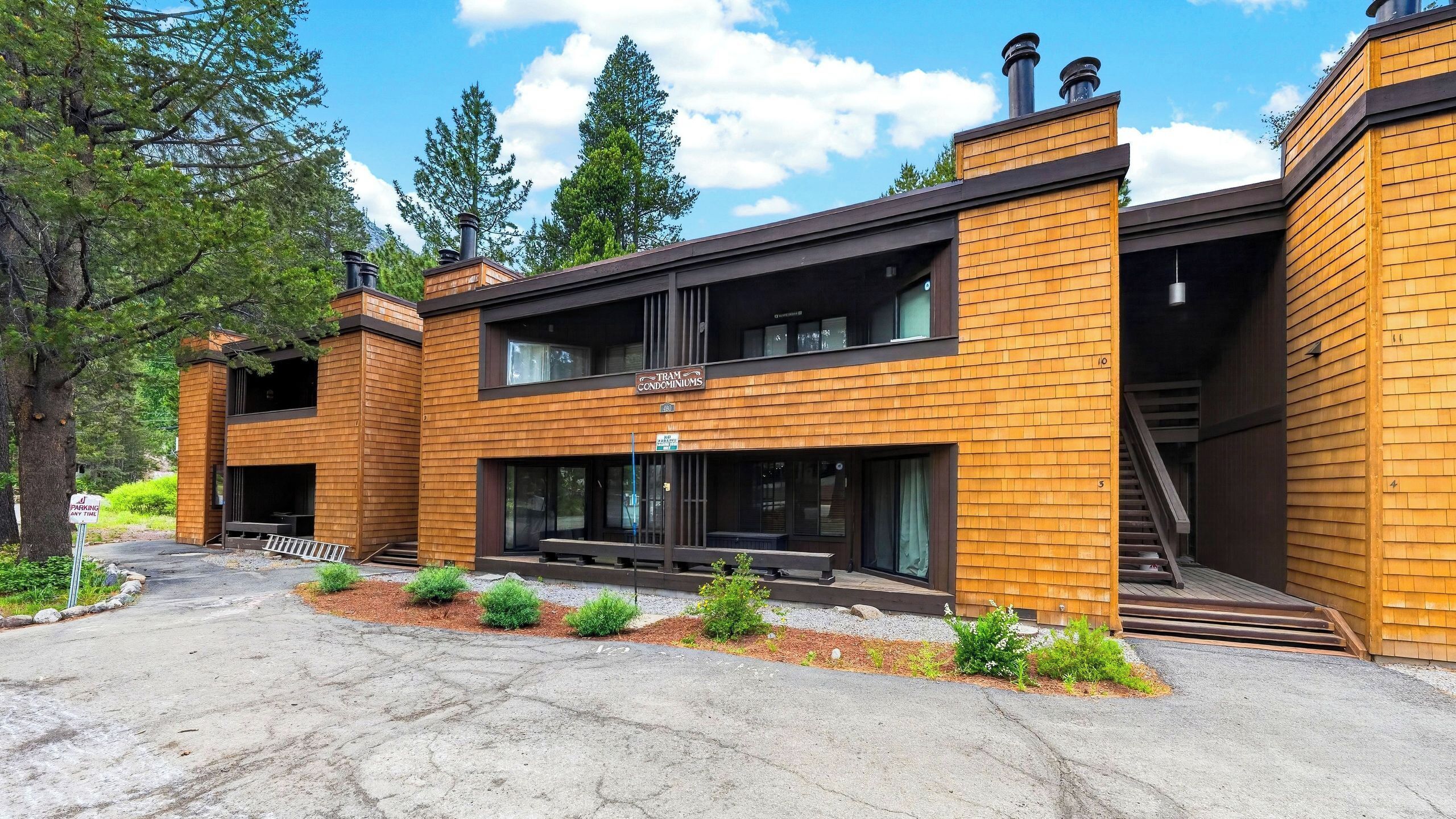 Un bâtiment moderne avec une façade en bois, de grandes fenêtres et une enseigne indiquant « RÉSIDENCES TRAM ».