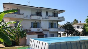 Un immeuble à plusieurs étages doté de balcons, d’une piscine et surplombant un ciel dégagé.