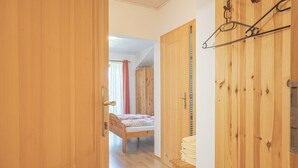 A wooden room with a bed, wardrobe, and a hanging coat rack. - Pivka Tripple Room With Balcony, Pivka, Slovenia (Pivka)