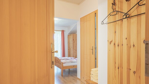 Una stanza in legno con un letto, un armadio e un attaccapanni.