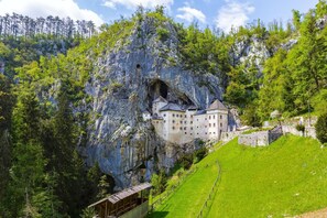 A castle nestled in a rocky cliff with a lush green landscape. - Pivka Tripple Room With Balcony, Pivka, Slovenia (Pivka)