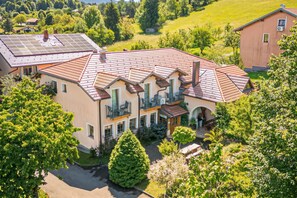 A large, multi-story house with a red-tiled roof, multiple balconies, and a well-maintained garden. - Pivka Tripple Room With Balcony, Pivka, Slovenia (Pivka)