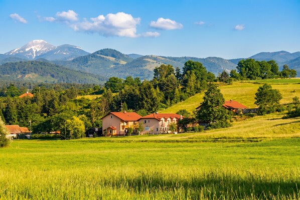 A rural landscape with houses, a mountain, and a clear sky.