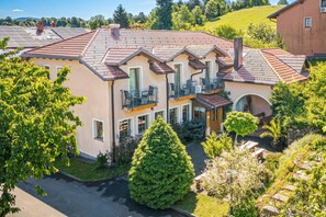 A two-story house with a balcony, a garden, and a driveway.