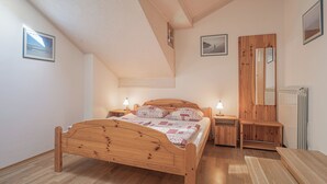 A bedroom with a wooden bed, bedside tables, a mirror, and a radiator. - Pivka Apartment With Terrace, Pivka, Slovenia (Pivka)