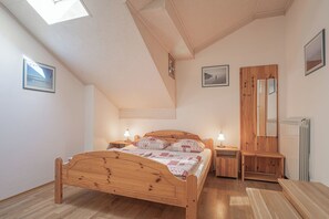 Ein Schlafzimmer mit einem Holzbett, Nachttischen mit Lampen, einem Holzschrank, einem Oberlicht und gerahmten Bildern an den Wänden.