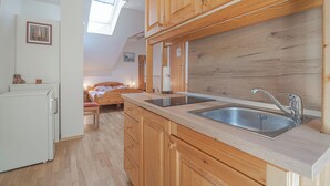 A kitchen with wooden cabinets, a sink, and a window above the countertop. - Pivka Apartment With Terrace, Pivka, Slovenia (Pivka)