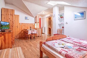 Een kamer met een bed, een bureau, een stoel, een tafel en een televisie.
