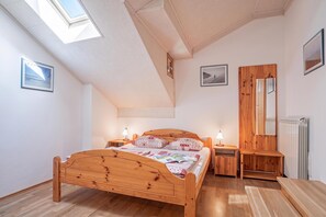 A bedroom with a wooden bed, bedside tables, a mirror, and a radiator. - Pivka Apartment With Terrace, Pivka, Slovenia (Pivka)