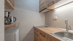 Eine moderne Küche mit Holzschränken, einer Edelstahl-Spüle und einer eingebauten Kaffeemaschine.