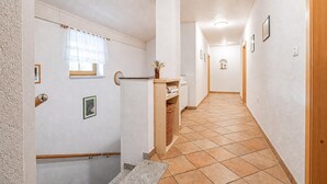 Ein Korridor mit einer Holztür, einem Heizkörper, einem Korbwesen und einem gerahmten Bild an der Wand.