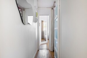 A narrow hallway with a wooden floor, a white door at the end, and a mirror on the wall. - Bright 1BDR Retreat in Paris 15th (Paris)