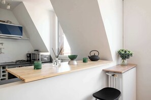 A modern kitchen with a wooden countertop, a kettle, a green bowl, and a vase with greenery. - Bright 1BDR Retreat in Paris 15th (Paris)