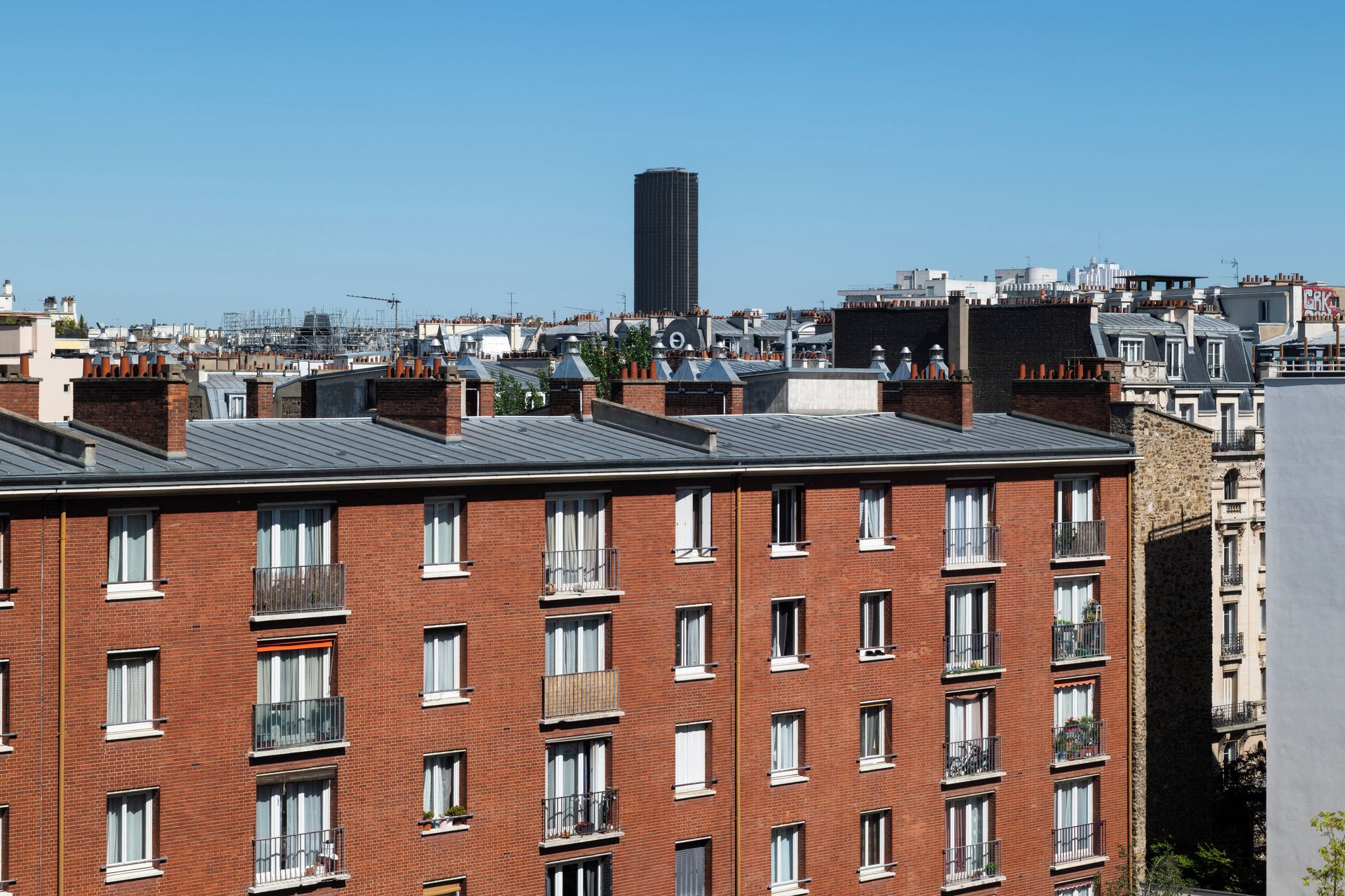 Un immeuble résidentiel à plusieurs étages, doté d’une façade en briques, de nombreuses fenêtres et de balcons.