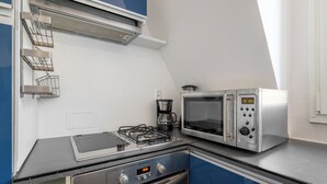 Een kitchenette met een gasfornuis, een magnetron en een koffiezetapparaat.
