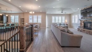 Ein geräumiges Wohnzimmer mit Kamin, eine Essecke mit Aussicht und eine Treppe mit Geländer.