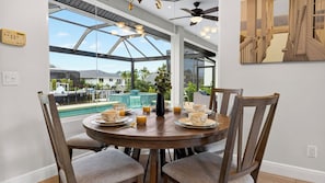 Ein Essbereich mit Blick auf einen Swimmingpool und ein Wintergarten.