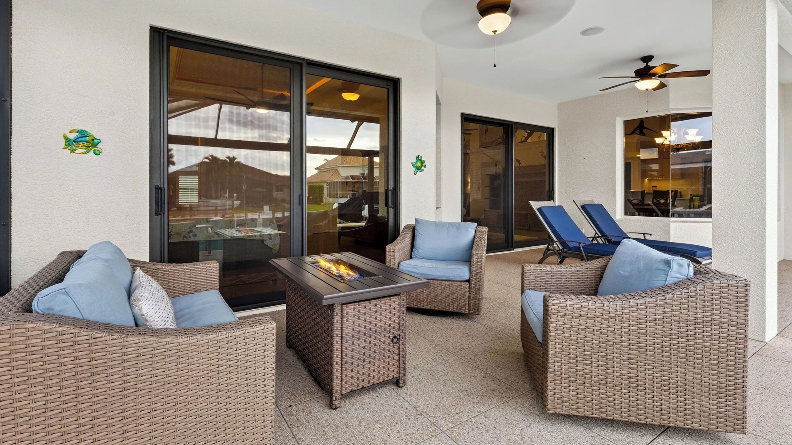 A covered outdoor seating area with wicker furniture and a fire feature.