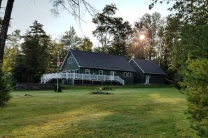Ein zweistöckiges Haus mit einer Veranda und einer Fahnenstange.