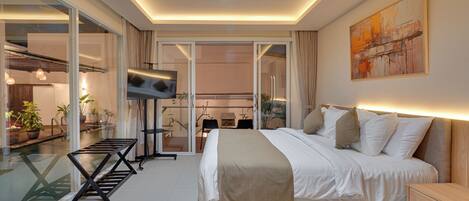 Un dormitorio moderno con cama, televisor y puerta corrediza de vidrio que da a un balcón.