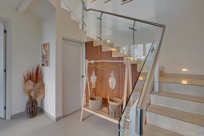 A modern interior with a glass staircase, wooden flooring, and decorative wicker baskets. - The Queeno Hill Villa - Nusa Dua (Nusa Dua)