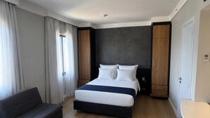 A modern hotel room with a large bed, a sofa, a desk, and built-in wardrobes. - Premium apartment in Tatuapé with pool, gym and garage included. (São paulo)