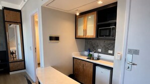A compact kitchen with a dining table, chairs, a microwave, and a refrigerator. - Premium apartment in Tatuapé with pool, gym and garage included. (São paulo)