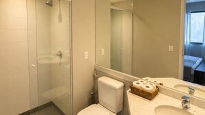 A modern bathroom with a glass-enclosed shower, a toilet, and a vanity with a mirror. - Premium apartment in Tatuapé with pool, gym and garage included. (São paulo)