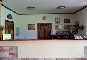 A reception area with a wooden door, framed pictures on the wall, and a stone wall at the bottom. - Changthai Comfort Guest House (Udon Thani)