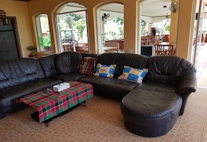 A living room with a black leather sofa, a plaid throw blanket, and a small table. - Changthai Comfort Guest House (Udon Thani)