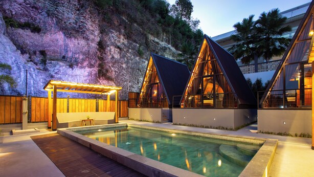 A modern pool area with wooden decking, a pergola, and two triangular glass-roofed structures. - EL Cabana (Kuta Selatan)