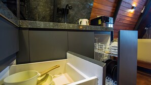 Una cocina con lavavajillas incorporado, cafetera y escurreplatos.