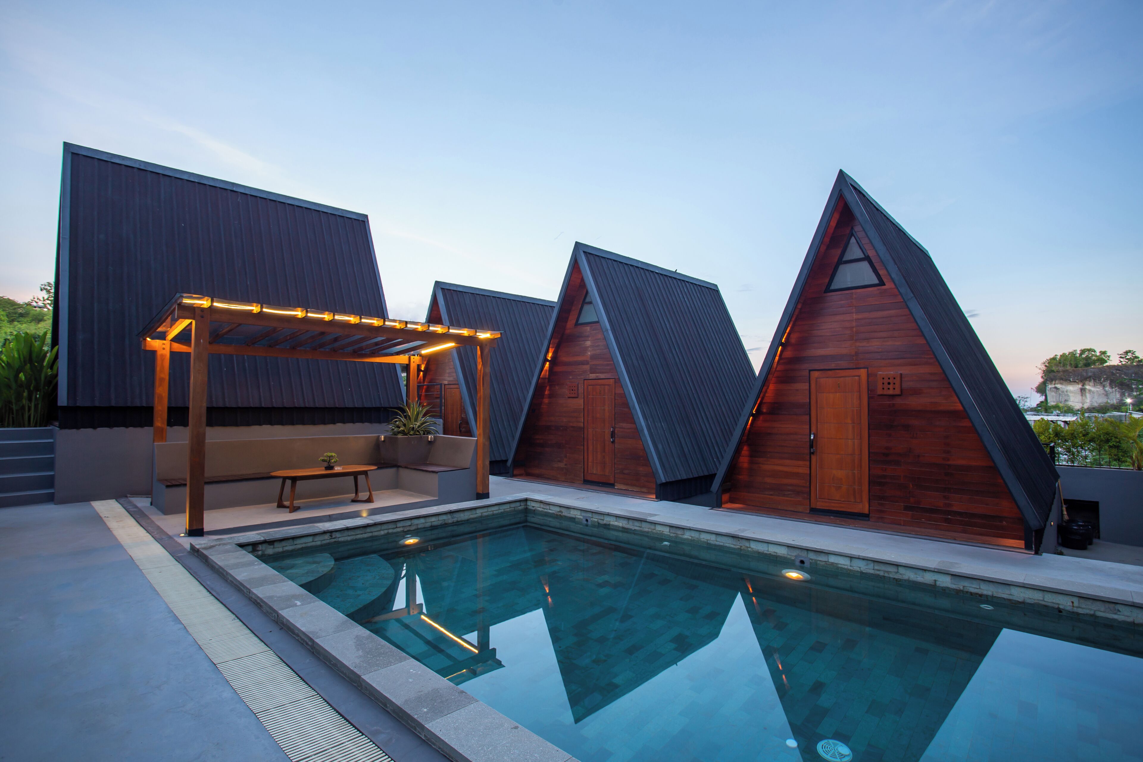 A modern pool area with a clear pool, wooden deck, and a pergola.