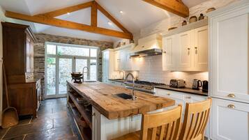 A kitchen with a wooden island, white cabinets, and a stone wall.