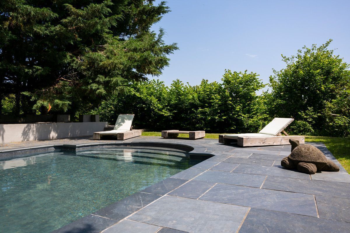 A swimming pool with lounge chairs and a stone sculpture.