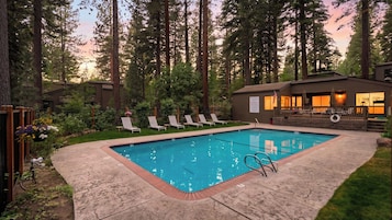 Piscina rectangular con borde de ladrillo, rodeada por una terraza de madera.