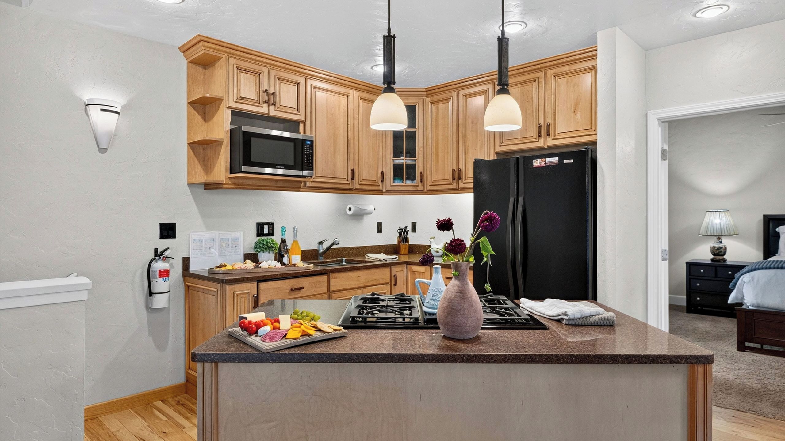 A modern kitchen with wooden cabinets, a black refrigerator, a microwave, and a gas stove.