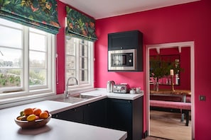 A kitchen with a sink, a microwave, and a toaster. There is a window with a view of the outside.