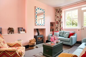 Una sala de estar acogedora con chimenea, un sofá, una mesita de centro y una estantería.