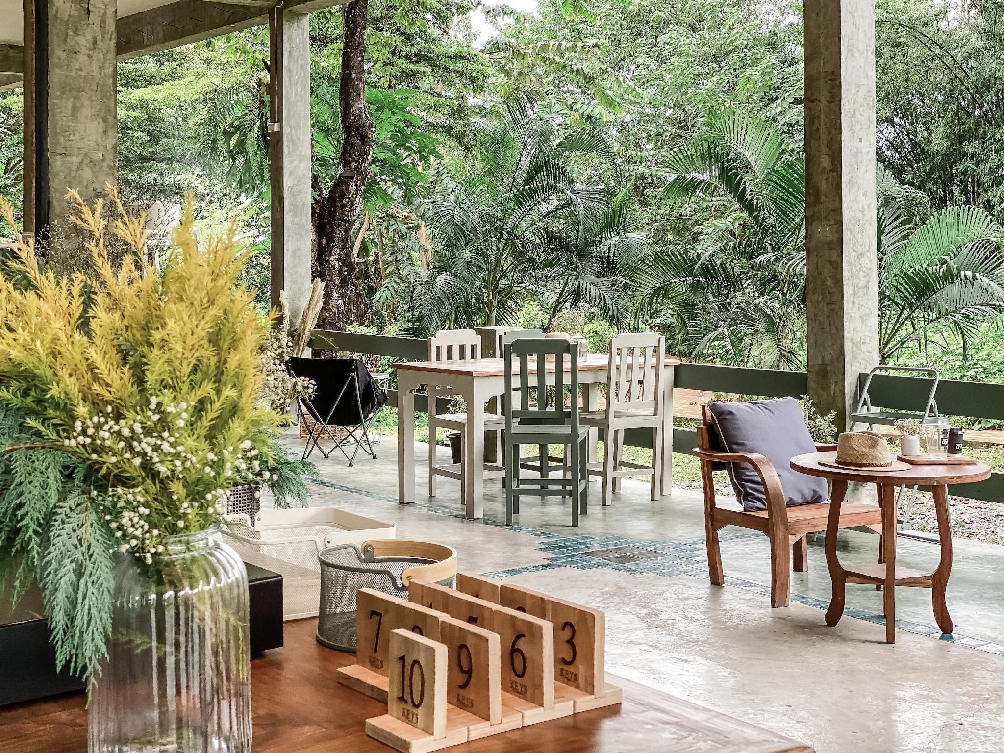 An outdoor seating area with a table and chairs, surrounded by greenery.