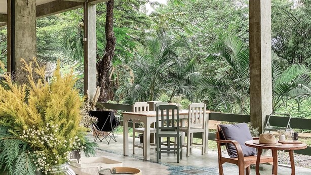 An outdoor seating area with a table and chairs, surrounded by greenery. - Keys Essential Resort (Pai)
