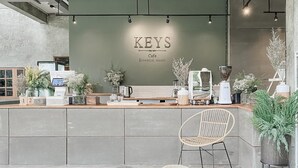 A KEYS cafe with a modern interior, a wooden counter, and a seating area with a wicker chair. - Keys Essential Resort (Pai)