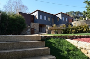 A modern two-story house with a stone staircase leading to the entrance, surrounded by a well-maintained garden. - Rio Moment S (Castelo de Paiva)