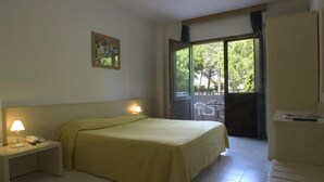 Una camera d'albergo con un letto, comodini, una scrivania e vista sull'esterno.